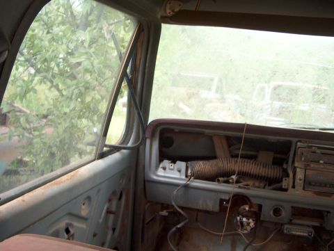 1979 Ford Bronco - Interior view of a derelict vehicle, with other vehicles visible in the background.