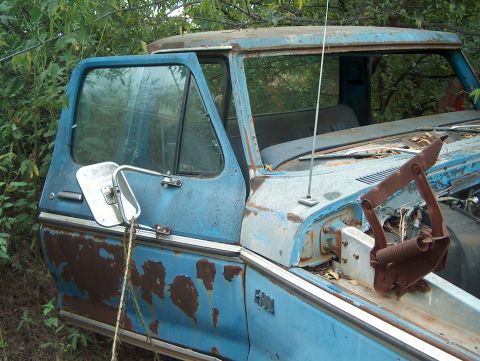 1979 Ford Bronco - This old truck cab is heavily rusted and appears to be abandoned in a wooded area.
