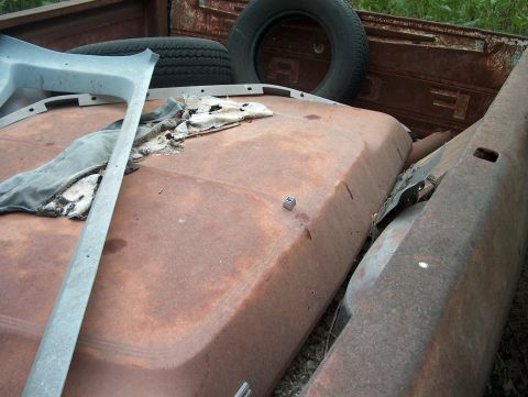 1979 Ford Bronco - Junk yard scene with various rusted vehicle parts, including a spare tire and interior trim pieces.