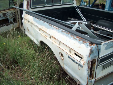 1979 Ford Bronco - A white pickup truck, possibly a 1979 Ford Ranger XLT, sits in a junkyard with another vehicle visible in the background.