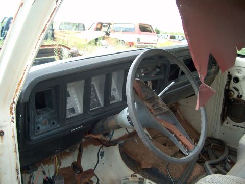1979 Ford Bronco - Interior view of a 1979 Ford Bronco in a junkyard, with other vehicles in the background.