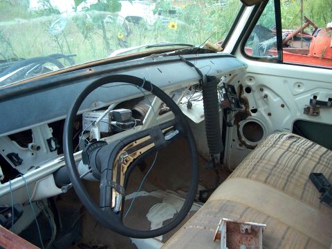 1979 Ford Bronco - The interior of a derelict vehicle shows signs of disrepair and missing parts, with visible wiring and a worn seat.
