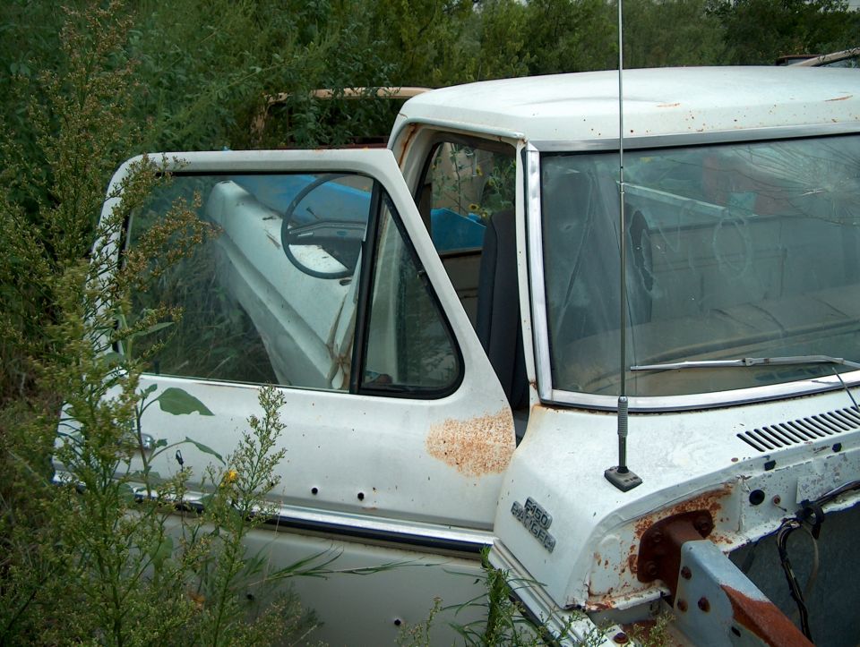 1979 Ford Bronco cab with open door, white, showing interior and rust spots