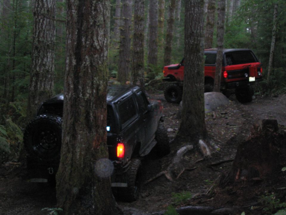 Black 1989 Ford Bronco with spare tire on rear, driving off-road