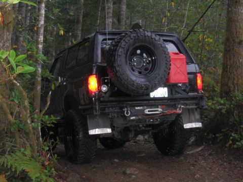 1989 Ford Bronco - Black 1989 Ford Bronco on a wooded trail, equipped for off-roading with a spare tire and gas can.