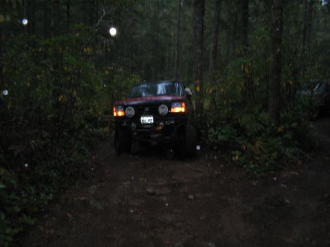 1989 Ford Bronco - Red 1989 Ford Bronco navigates a wooded path during rainy weather.