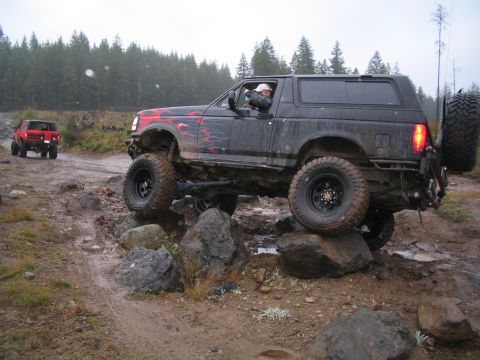 1989 Ford Bronco - A modified 1989 Ford Bronco navigates a rocky trail, with another SUV visible in the background.
