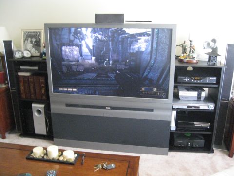 1988 Ford Bronco - A living room scene a large television displaying a video game, surrounded by shelves with electronics and speakers.