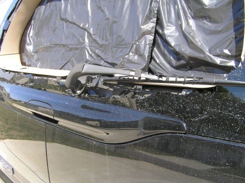 2000 Ford Excursion - The rear liftgate glass of a black 2000 Ford Excursion is shattered and covered with plastic sheeting, with the wiper mechanism visible.
