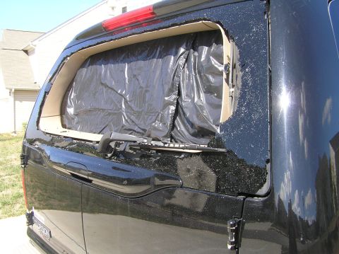 2000 Ford Excursion - The rear liftgate glass of a black 2000 Ford Excursion is shattered and covered with black plastic sheeting.