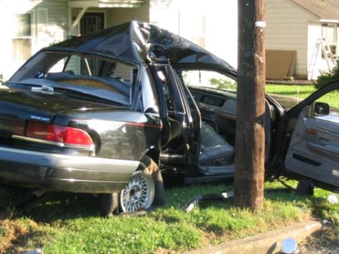 1999 Ford Crown Victoria - This black sedan sustained severe damage to its roof and side after colliding with a utility pole.