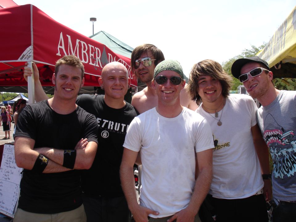 Group of six men smiling in front of a red tent
