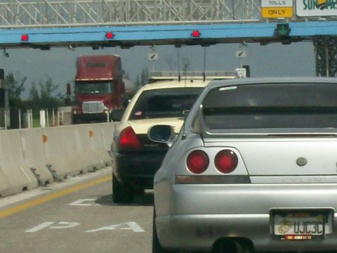 2003 Mercury Marauder - Traffic moves through a toll plaza with a silver sports coupe and a police car visible.