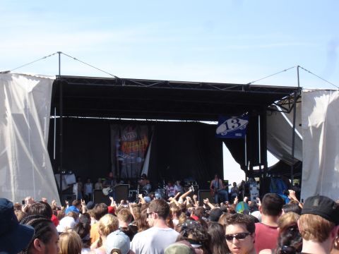 1992 Ford F-150 - A band performs on an outdoor stage at a concert, with a large crowd gathered in front of them.