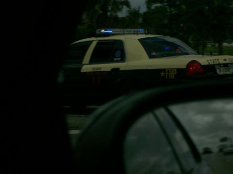 2003 Mercury Marauder - A two-tone police car, marked FHP, is seen from the side with its emergency lights activated.