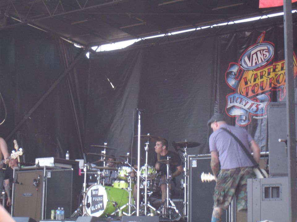 Band performing on a stage with a Vans Warped Tour banner