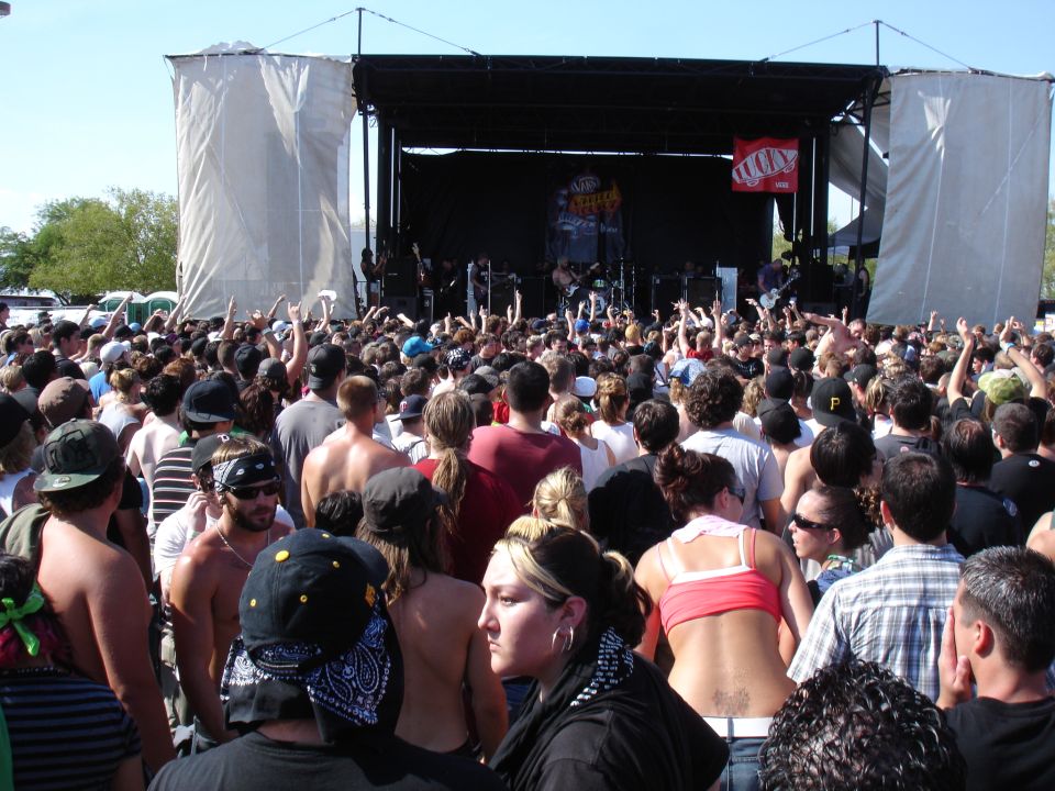Outdoor concert crowd facing a stage with a band performing