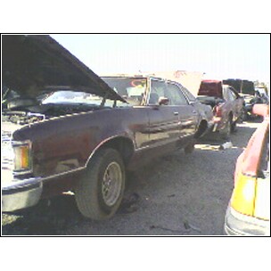 1973 Ford Ranchero - A Ford Ranchero sits in a junkyard with its hood open, surrounded by other vehicles.