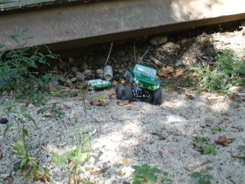 1996 Ford Bronco - A toy truck is parked on gravel near discarded cans, under a concrete overhang.