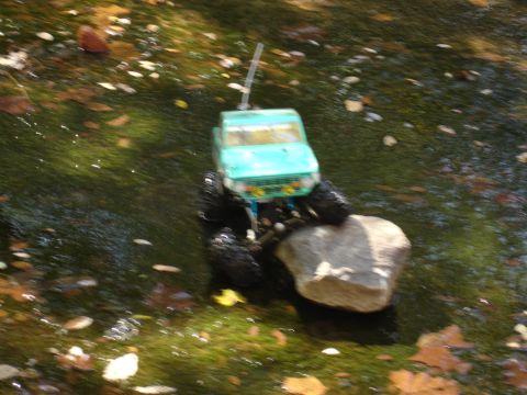 1996 Ford Bronco - Toy RC truck navigating a rocky stream bed with fallen leaves.