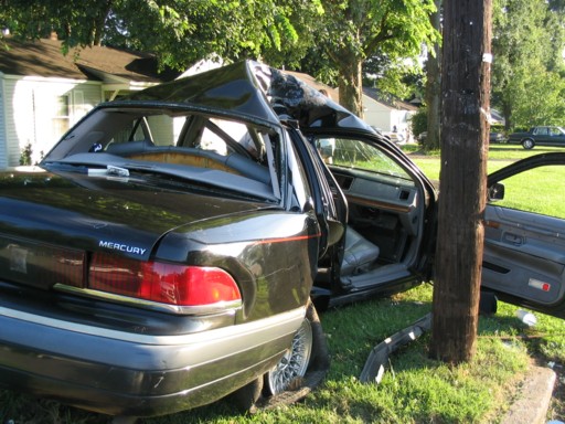 Mercury Grand Marquis with severely damaged roof after hitting a pole. Driver door is open