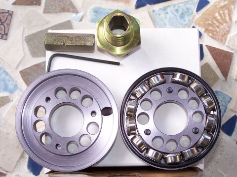 1989 Ford Bronco - A collection of automotive parts, including a pulley, bearing, and tools, are laid out on a tiled surface.