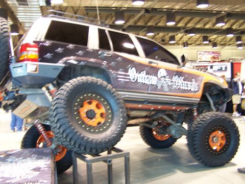 1989 Ford Bronco - This heavily modified SUV features large off-road tires, custom suspension, and distinctive 'Outlaw Offroad' graphics.