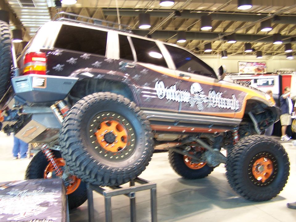 Custom lifted SUV with orange beadlock wheels and 'Outlaw Offroad' graphics