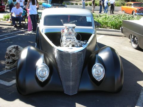 1998 Ford Crown Victoria - Front view of a black custom coupe with a chrome supercharged engine poking through the hood at a car show.