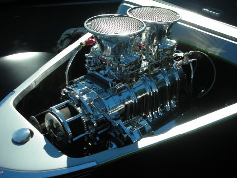 1998 Ford Crown Victoria - Close-up of a polished roots supercharger topped with twin carburetors and chrome scoops in a custom car's engine bay.