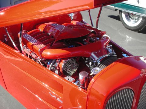 1998 Ford Crown Victoria - open engine bay of an orange hot rod fitted with a red BMW V12 engine and chrome intercooler plumbing.