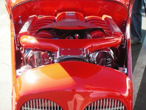 1998 Ford Crown Victoria - Front view into a red hot rod's engine bay showing a red V12 engine with V12-marked valve covers.