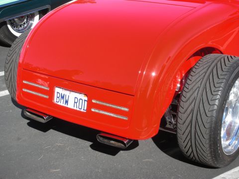 1998 Ford Crown Victoria - Rear of a red hot rod with chrome side-exit exhaust tips and a California plate reading BMW ROD.