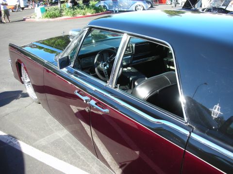 1998 Ford Crown Victoria - Side view of a dark maroon classic luxury hardtop coupe with chrome trim and wire wheels, parked at an outdoor car show.
