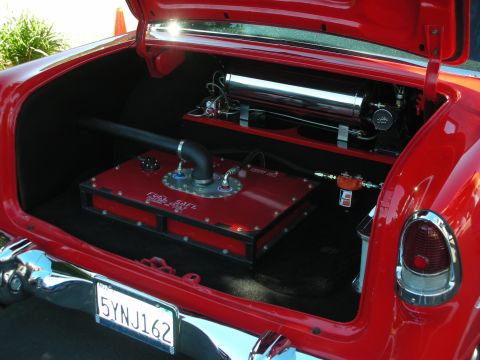 1998 Ford Crown Victoria - Open trunk of a red classic car displaying a custom red fuel cell, chrome air tank and tail light, with California plate 5YNJ162.