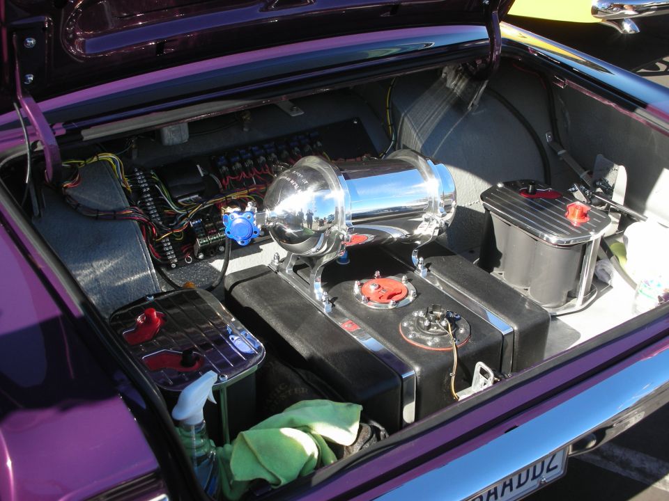 Open trunk of a purple custom car with chrome air tank, fuel cell and battery setup