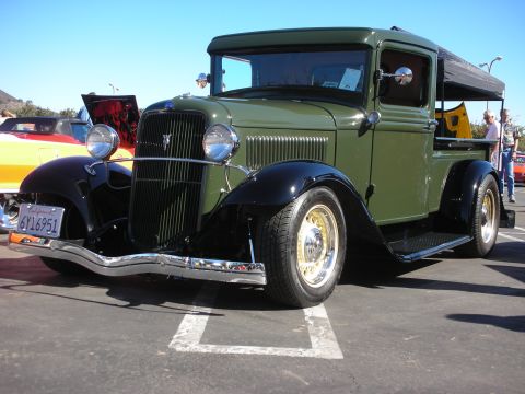 1998 Ford Crown Victoria - green-and-black 1930s Ford pickup hot rod with chrome bumper parked at an outdoor show, California plate 6Y16951.