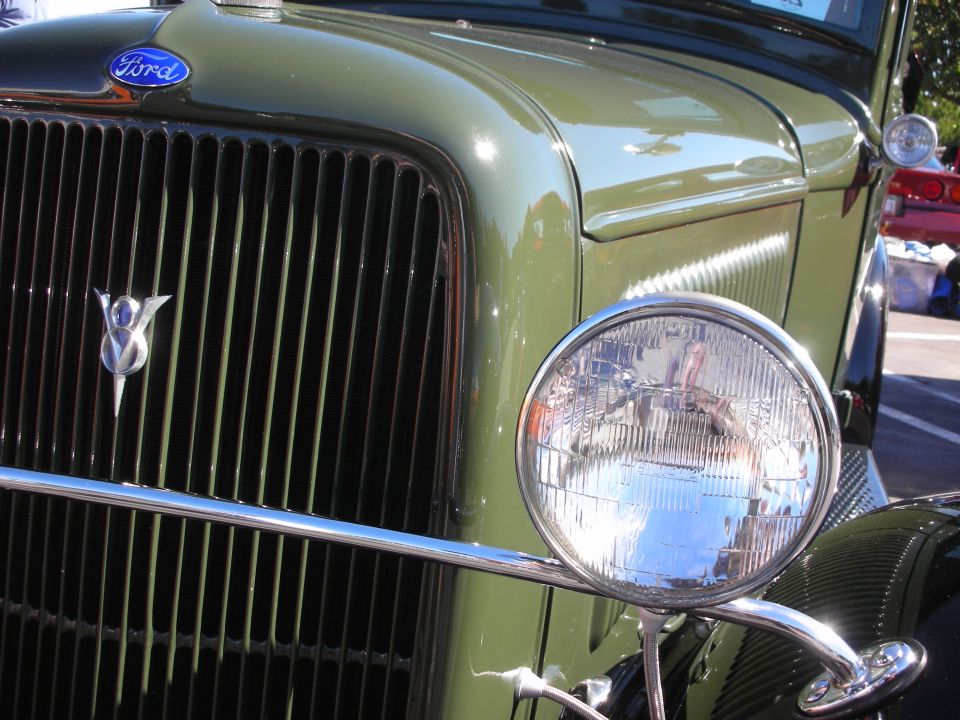Front grille close-up of a green vintage Ford showing Ford emblem and V8 badge