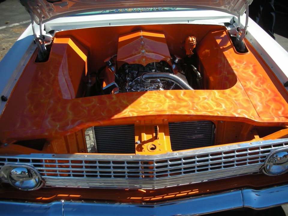 Engine bay of a custom car with orange real-flame airbrushed paint and chrome engine
