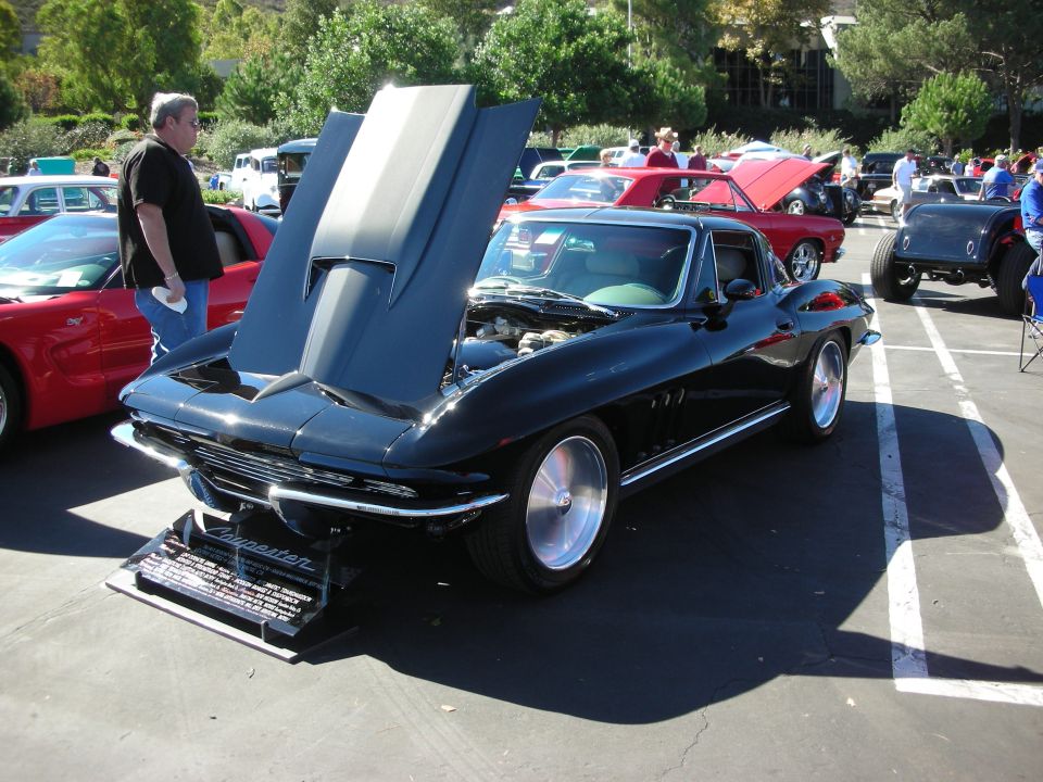 Black Chevrolet Corvette Sting Ray coupe with open hood at an outdoor car show