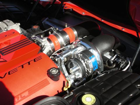 1998 Ford Crown Victoria - red-trimmed Corvette engine fitted with a polished belt-driven supercharger, orange ignition wires, and chrome plumbing under the hood.