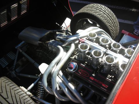 1998 Ford Crown Victoria - mid-mounted V8 with individual throttle-body stacks, swept tubular headers, and a Ford Racing valve cover sits behind the seats next to a r…