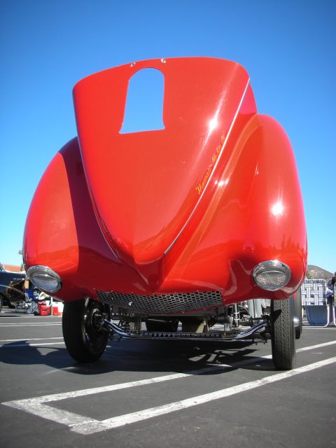 1998 Ford Crown Victoria - glossy red hot rod coupe photographed head-on under blue sky, riding high on an exposed tube front axle and beam suspension.