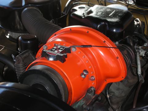 1998 Ford Crown Victoria - vintage round orange oil-bath air cleaner with a crest badge mounted atop an engine in a black-painted engine bay.