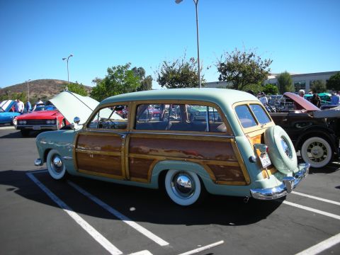 1998 Ford Crown Victoria - Rear three-quarter view of a green woodie station wagon showing wood side paneling and a rear-mounted spare-tire cover.