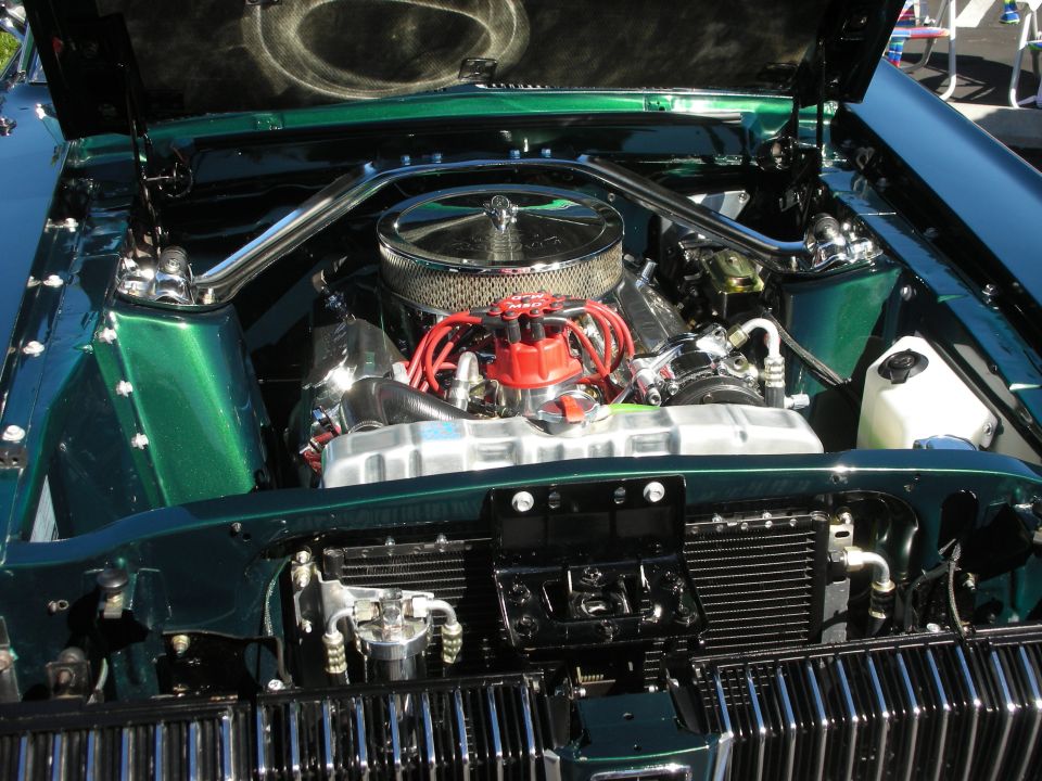 Chevrolet V8 engine with chrome air cleaner and red plug wires in green car