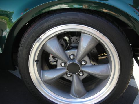 1998 Ford Crown Victoria - Close-up of a gray-painted five-spoke wheel with a disc brake and low-profile tire on a dark-green car.