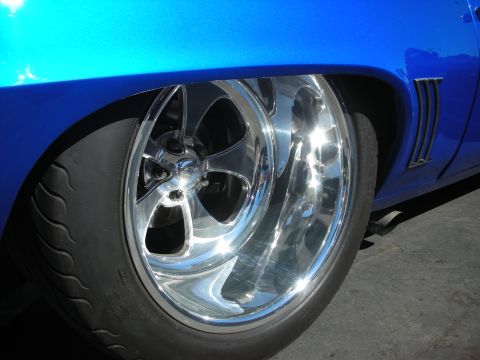 1998 Ford Crown Victoria - Close-up of a bright, polished five-spoke wheel and low-profile tire on a vivid blue car.