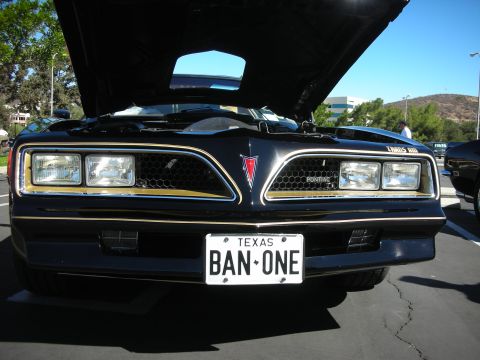 1998 Ford Crown Victoria - Front grille of a black Pontiac Firebird Trans Am with quad headlights and a Texas BAN-ONE license plate.