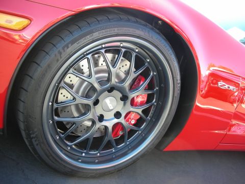 1998 Ford Crown Victoria - Close-up of a red sports car's multi-spoke gunmetal wheel, drilled brake rotor and red caliper, with a Z06 fender badge.